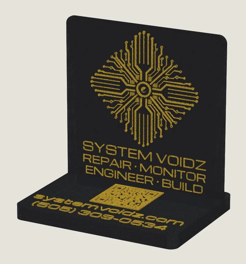 Black desk sign with the System Voidz circuit logo, name, and tagline raised in gold, standing in a slotted base printed with a QR code, the web address, and phone number.